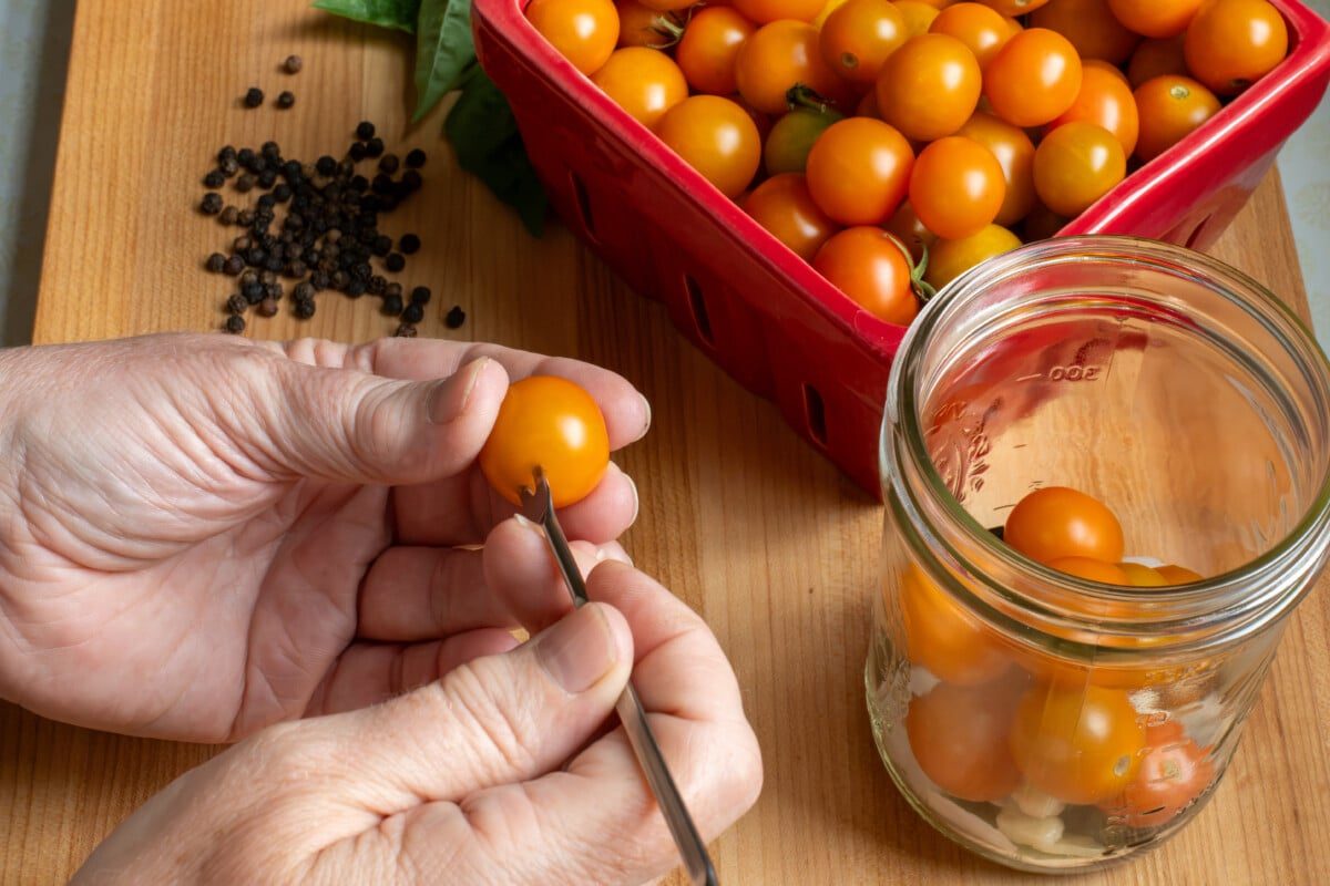 Woman's hands piercing a cherry tomato with a skewer